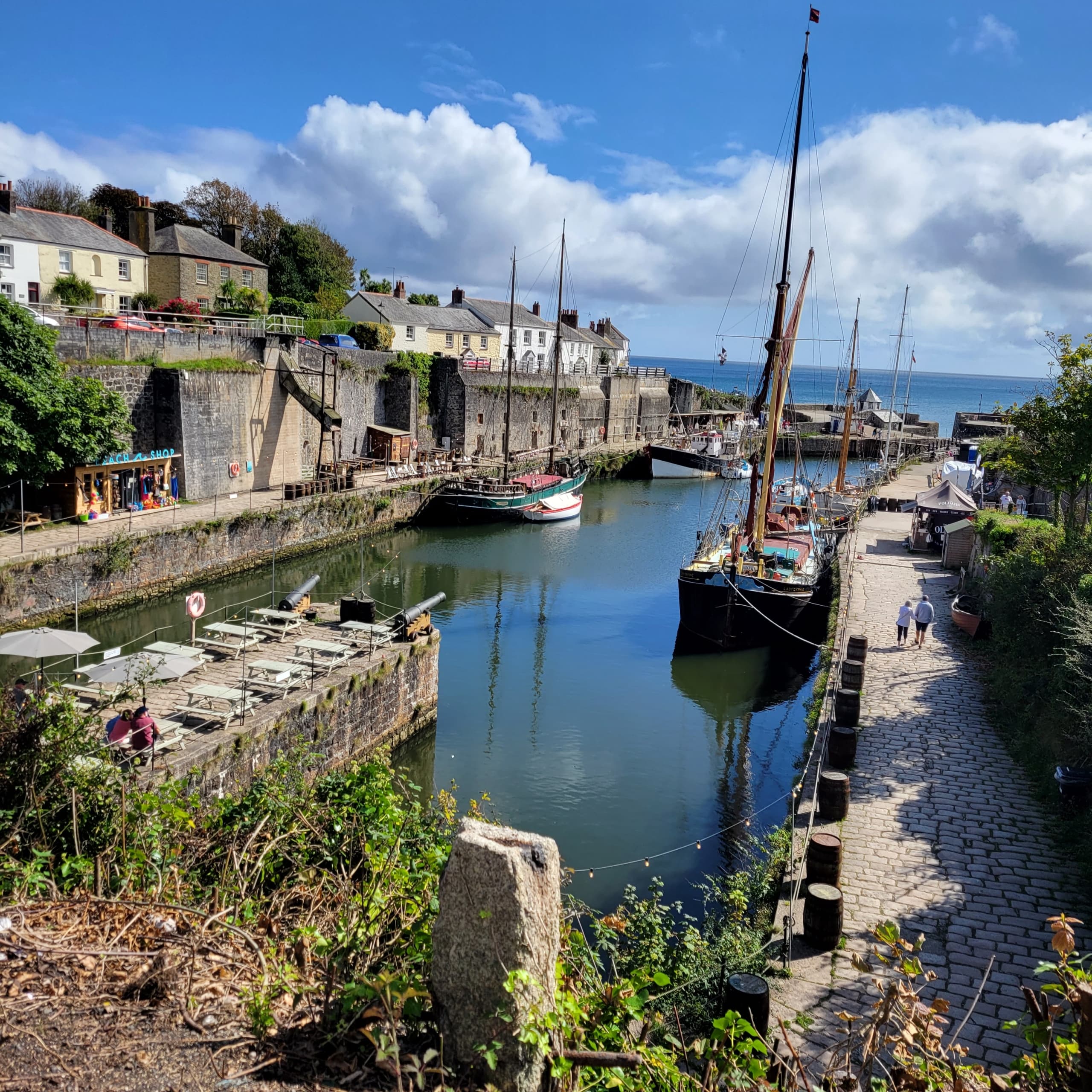 Tall ships moored in Charlestown harbour beneath white clouds